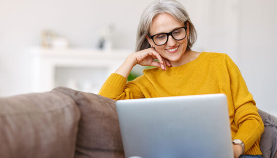Woman sitting on couch smiling at laptop
