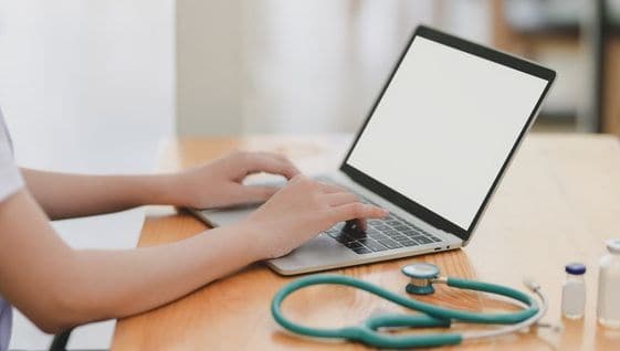 Person on a laptop with medical tools next to it on the table