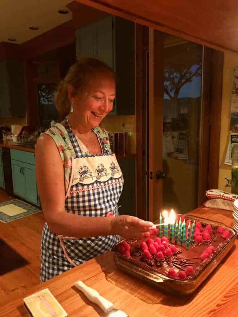 A woman in an apron lighting candles on a homemade cake