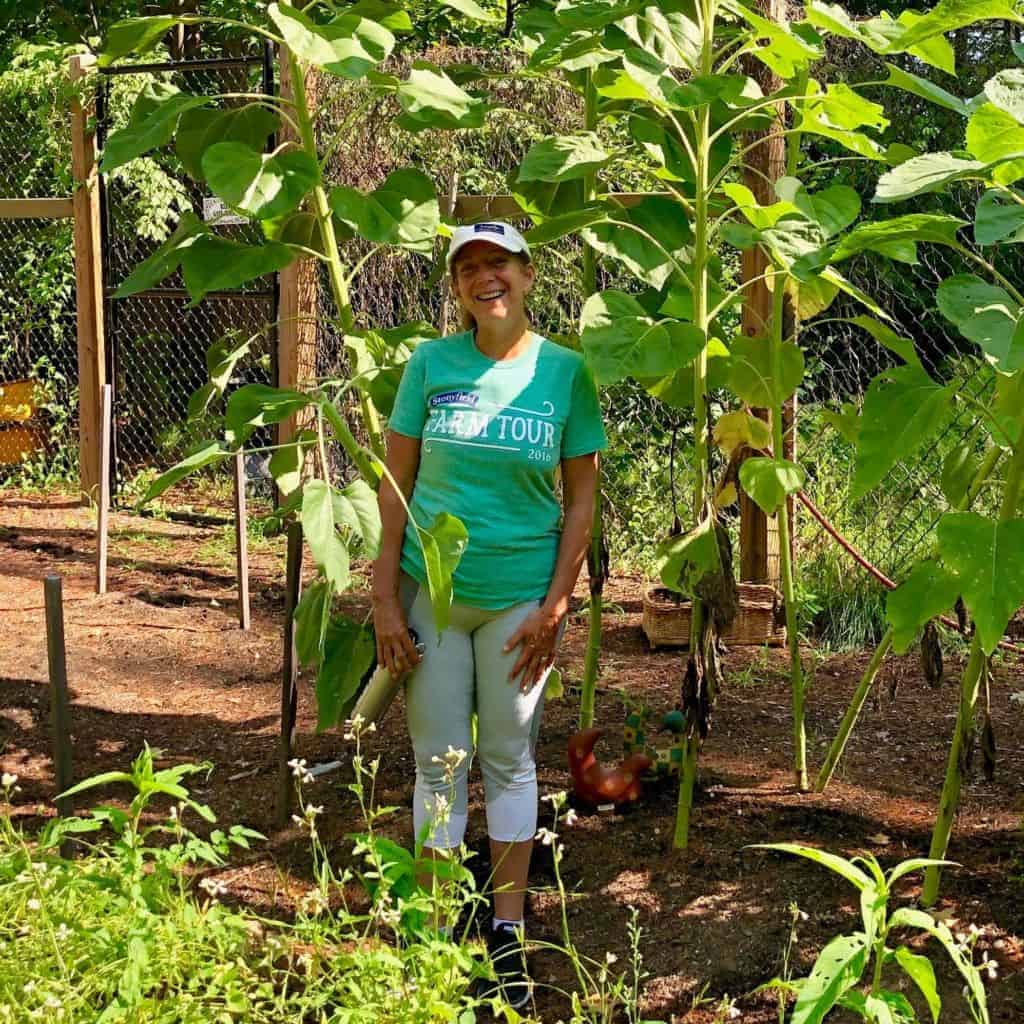 A woman standing smiling at the camera in a garden