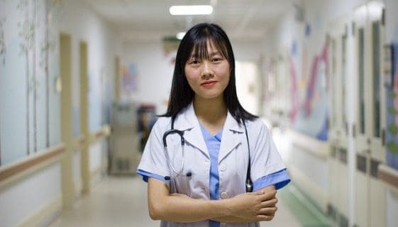 A doctor standing in a hallway with her arms crossed