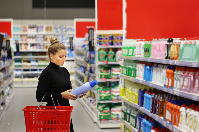 Woman looking at cleaning supplies in a grocery store aisle