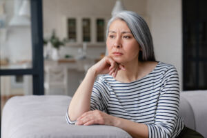 Woman sitting on couch with an upset, thoughtful look on her face