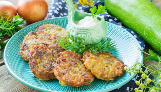 Potato pancakes and zucchini fried in a pan on a wooden background