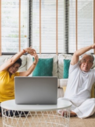 A man and woman stretching while looking at a laptop together